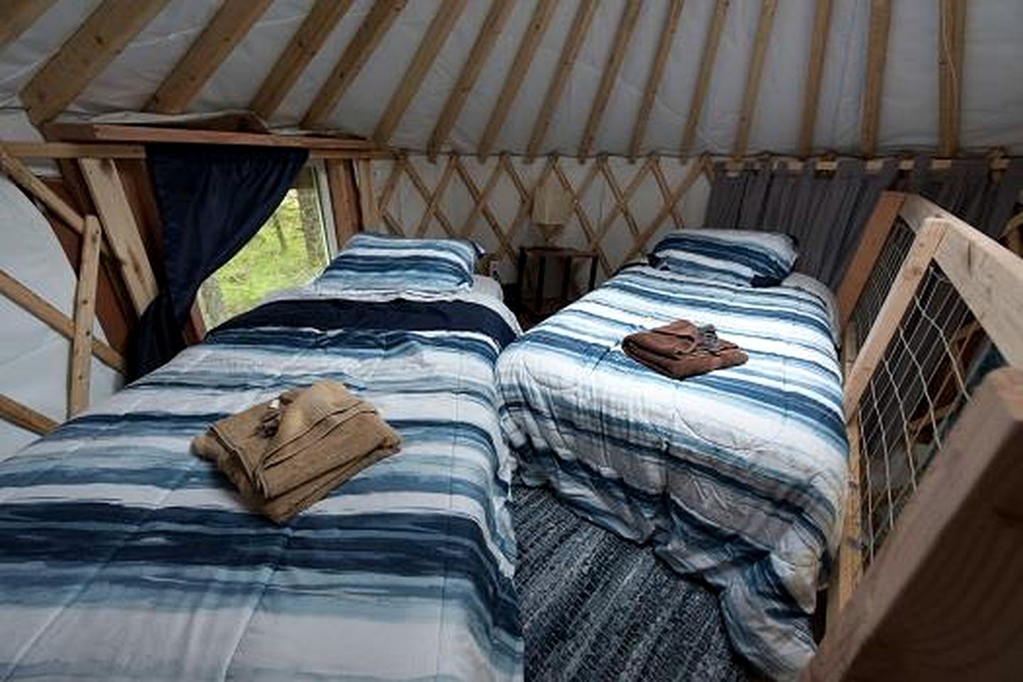 Une tente avec deux lits, chacun étant équipé d’une couverture à rayures et d’un oreiller.