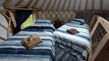 A tent with two beds, each with a striped blanket and a pillow.