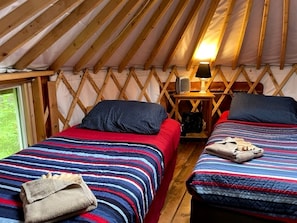 Ein gemütliches Interieur mit zwei Betten, einem Nachttisch und einer Lampe.