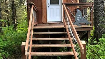 A wooden cabin with a door, a staircase, and a sign.