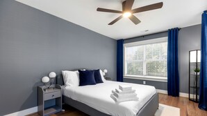 Une chambre à coucher moderne, avec un lit, une table de chevet et un ventilateur de plafond.