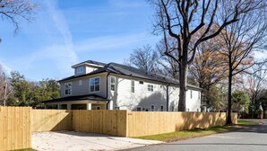 Une maison à deux étages avec un garage, une clôture en bois et un ciel dégagé.