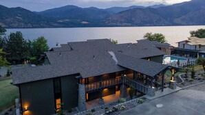 A modern house with a stone facade, a covered patio, and a view of a lake and mountains. - Designer Lakefront Condo E3, Wapato Point Chelan (Manson)