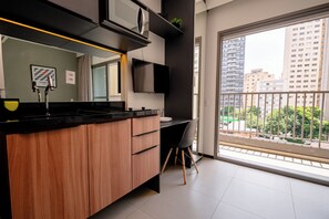 A modern bathroom with a black countertop, wooden cabinets, a mounted TV, and a large window with a city view. - Vnc consolation apt 614 (São Paulo)