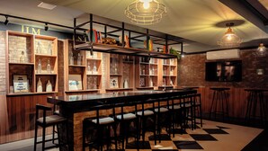 A bar area with a long counter, multiple stools, and shelves with various items. - Vnc consolation apt 614 (São Paulo)