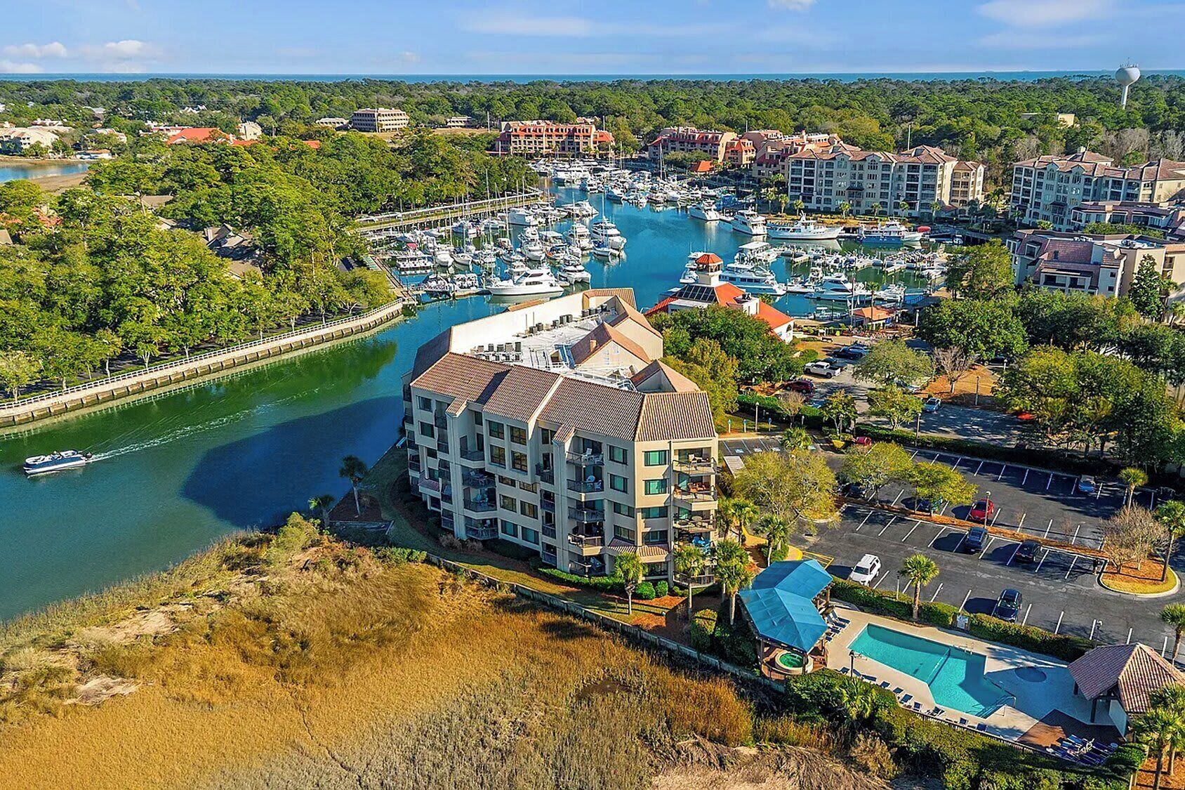 A marina with boats, a swimming pool, and a hotel with multiple floors and balconies.