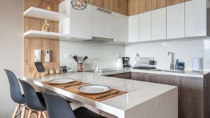 Una cocina moderna con armarios blancos, una isla central con asientos y una pared decorativa de madera.