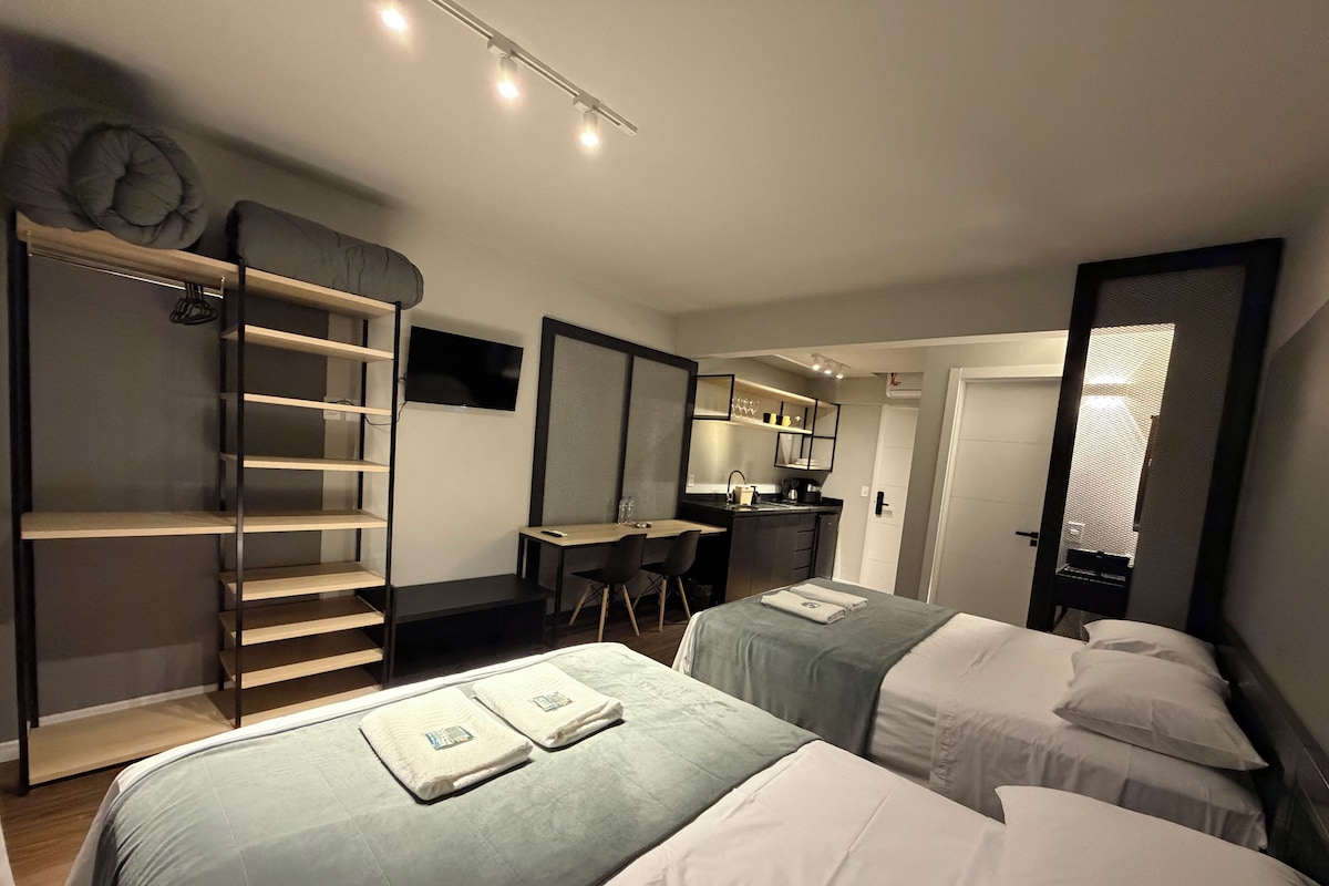 Une chambre d’hôtel avec deux lits, un bureau, une armoire et une kitchenette.