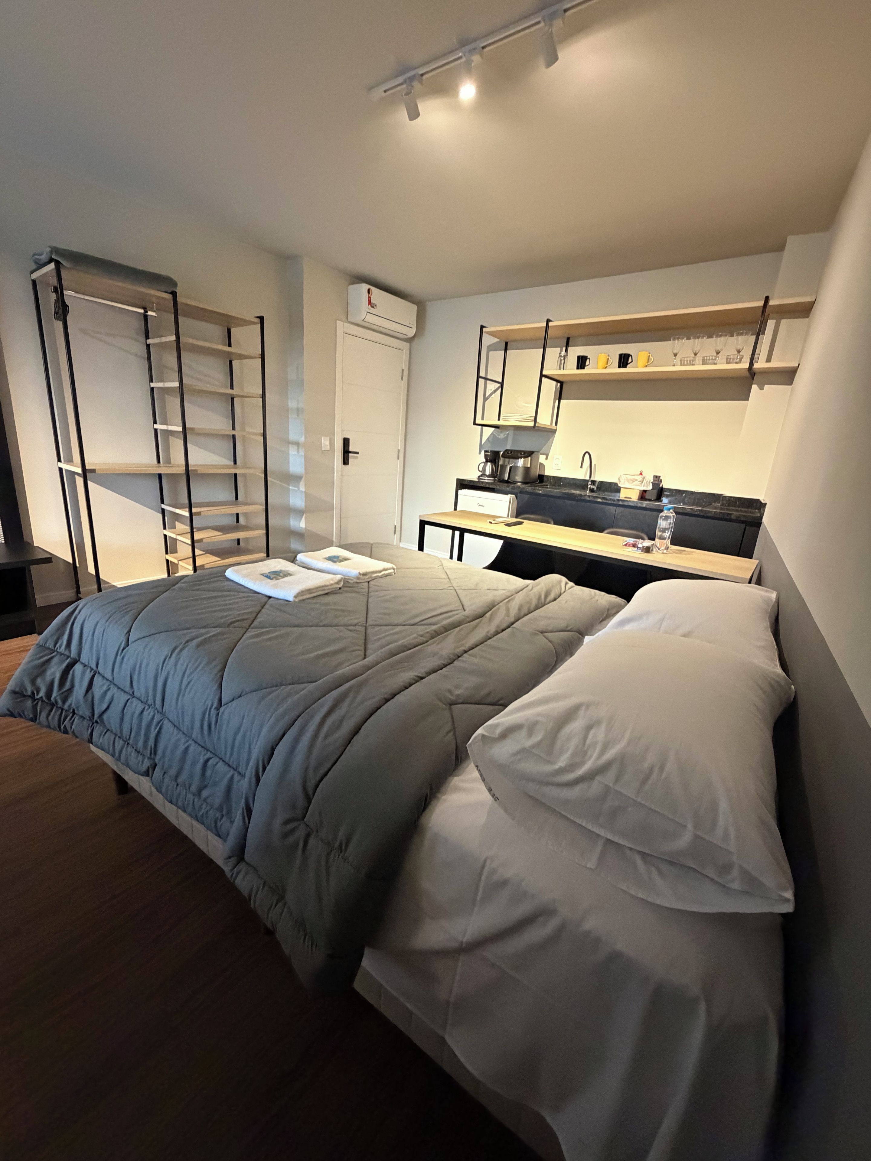 Un dormitorio con cama, escritorio, silla, armario y baño.