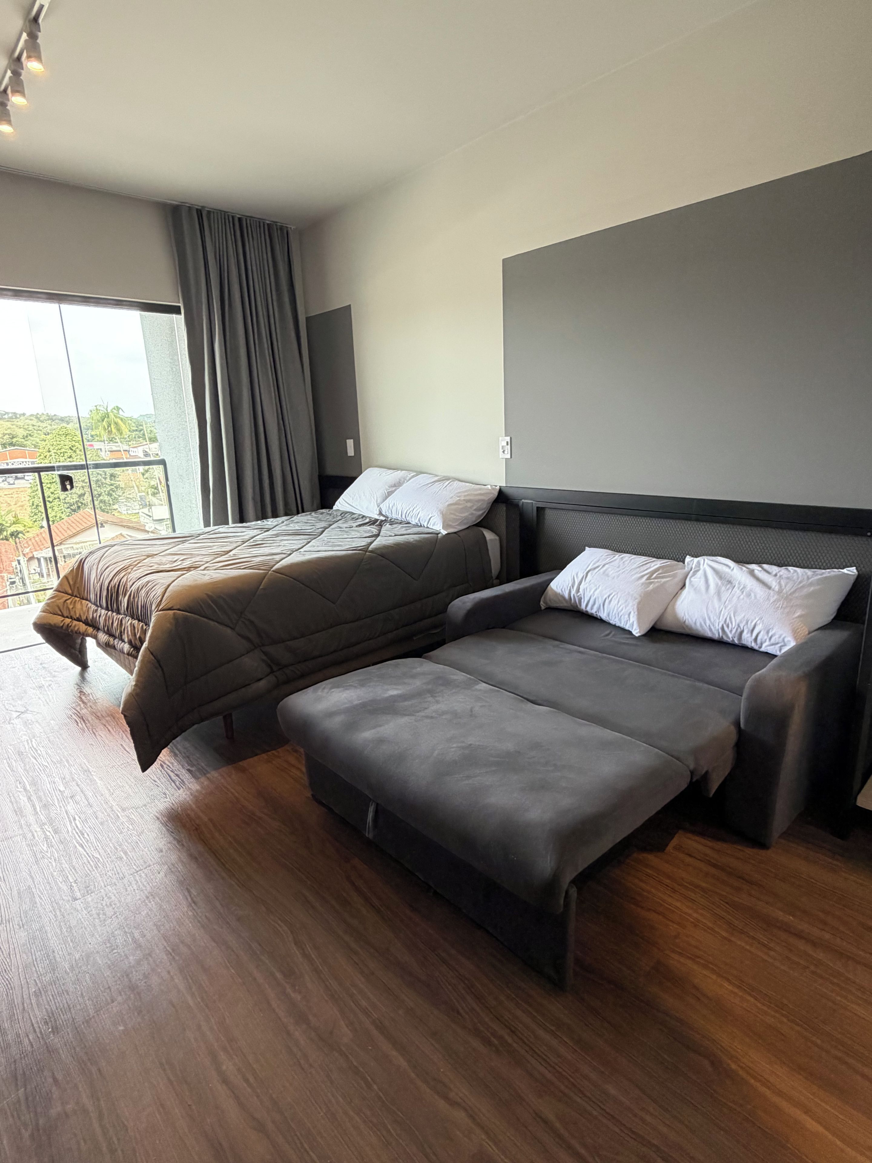 Un dormitorio moderno con una cama, un sofá y un ventanal grande.