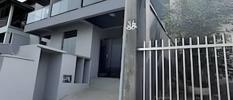 Un edificio de varios pisos con entrada protegida y camino de acceso pavimentado.