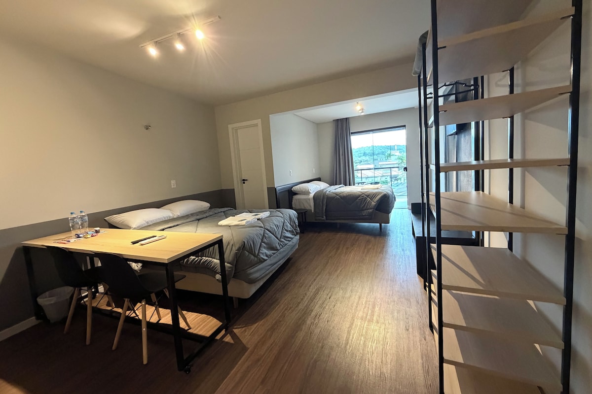 Une chambre d’hôtel de taille réduite, comprenant un lit, une petite table et une chaise. Une fenêtre offre une vue sur l’extérieur.