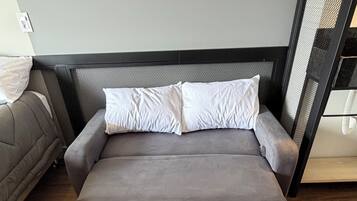 A modern bed with a grey mattress and white pillows in a room with wooden flooring.