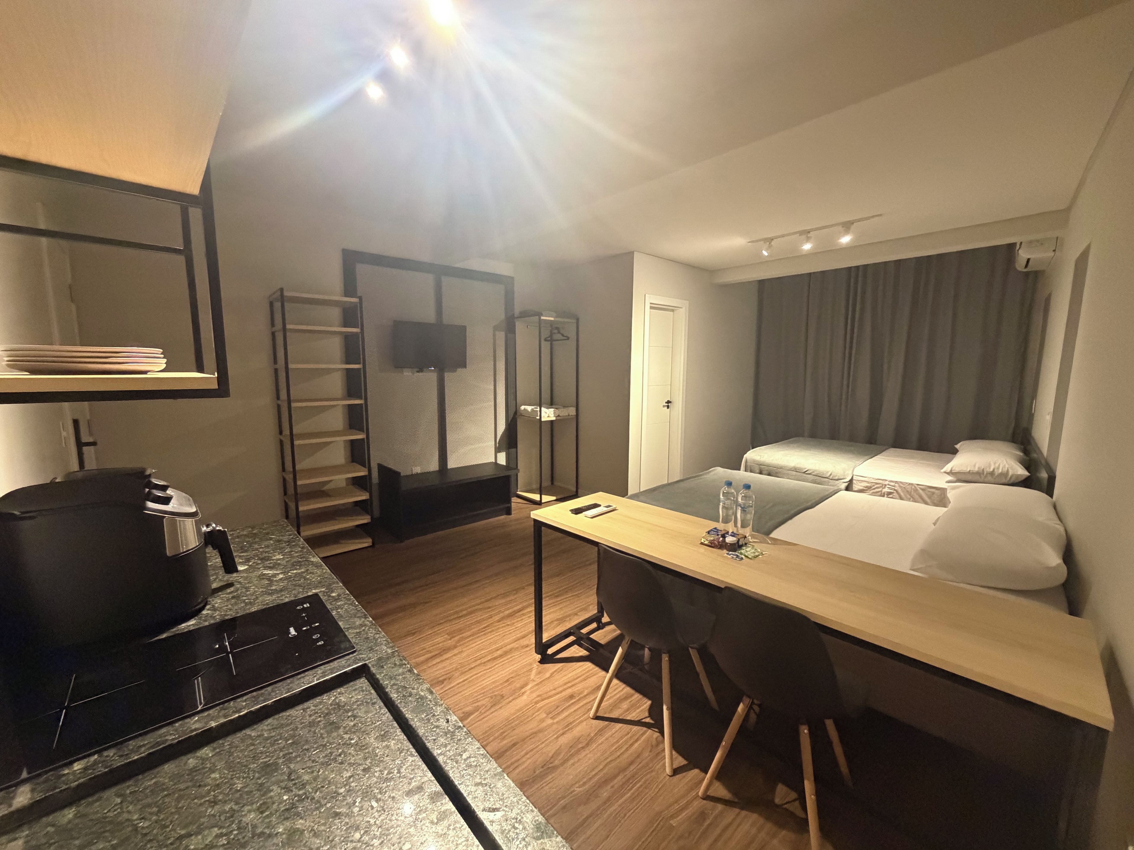 A hotel room with a bed, a desk with a chair, a TV, and a wardrobe.