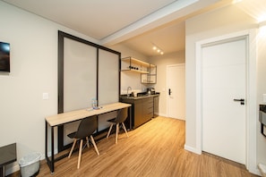 A compact kitchen with a sink, countertop, and a small dining area with a table and chairs. - Apez Smart Studio (Joinville)