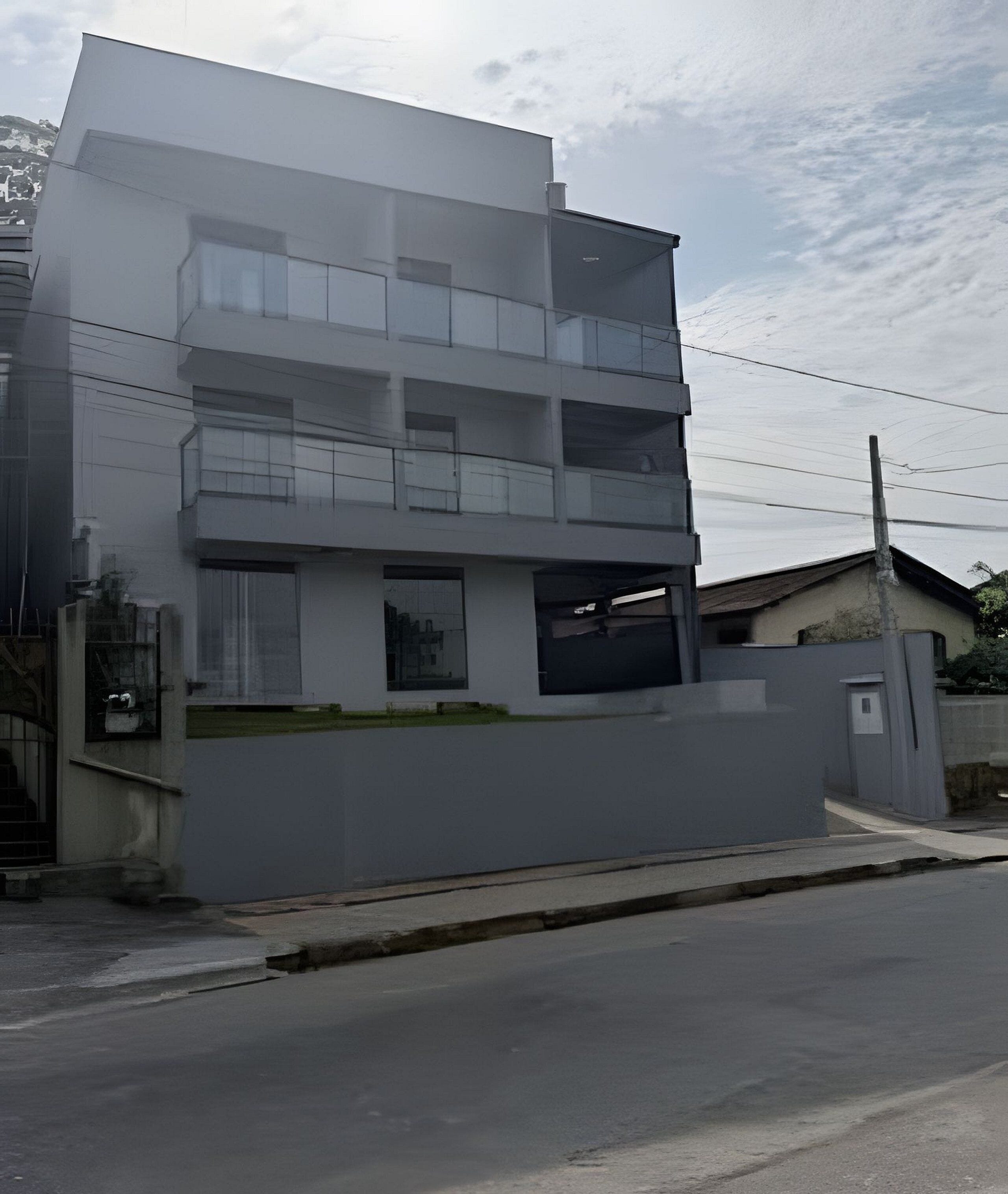 A modern multi-story building with a flat roof, large windows, and a gated entrance.