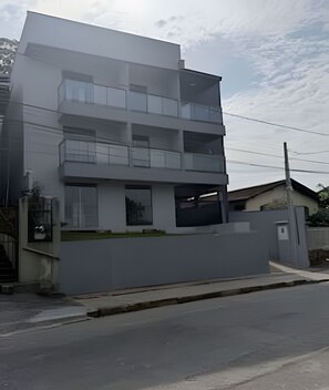 A modern multi-story building with a flat roof, large windows, and a gated entrance. - Apez Smart Studio (Joinville)