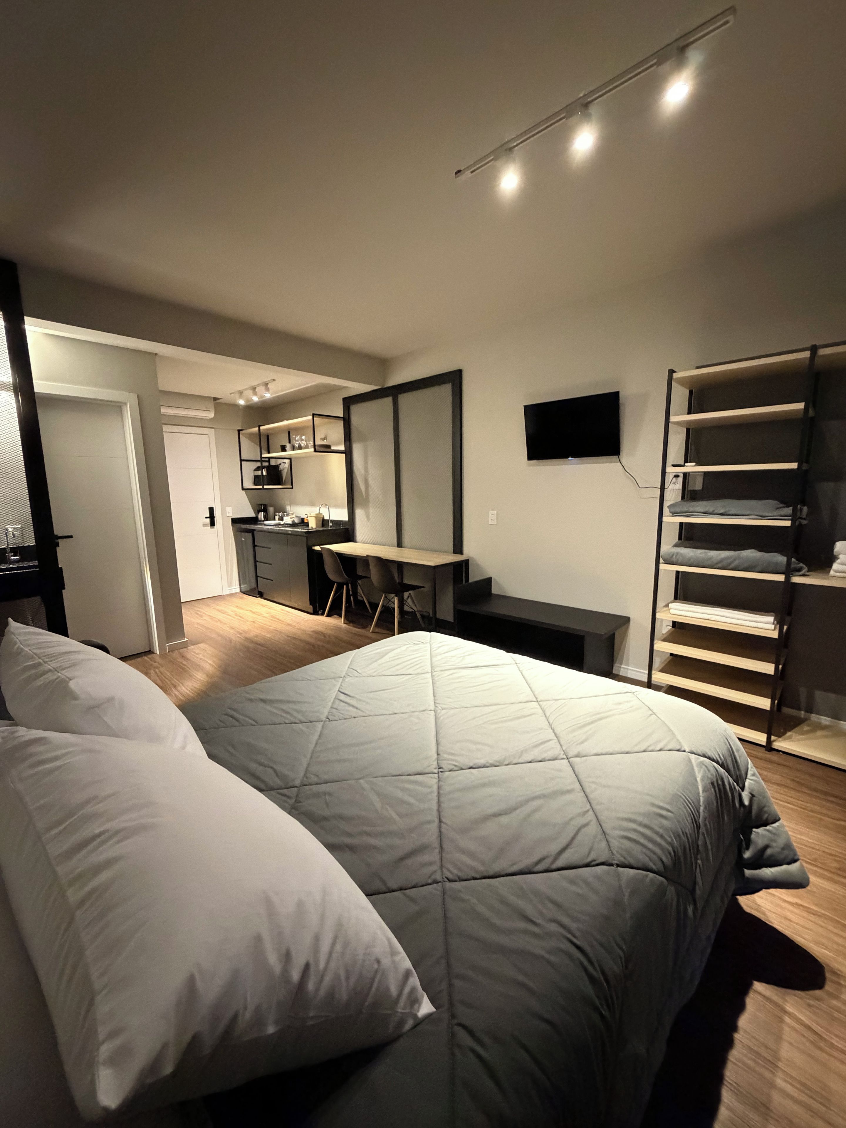 Un dormitorio moderno con cama, escritorio y televisión.