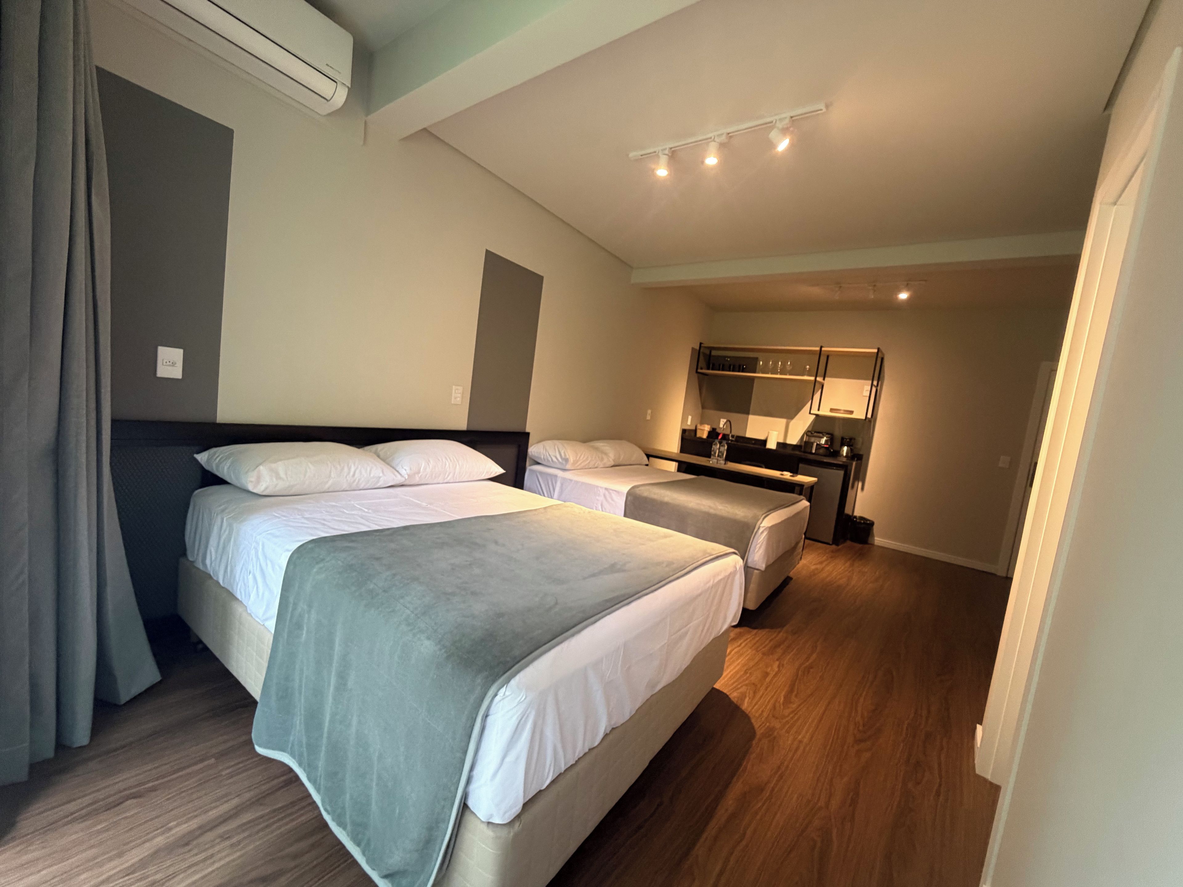 Habitación de hotel con dos camas, una kitchenette pequeña y un espejo.