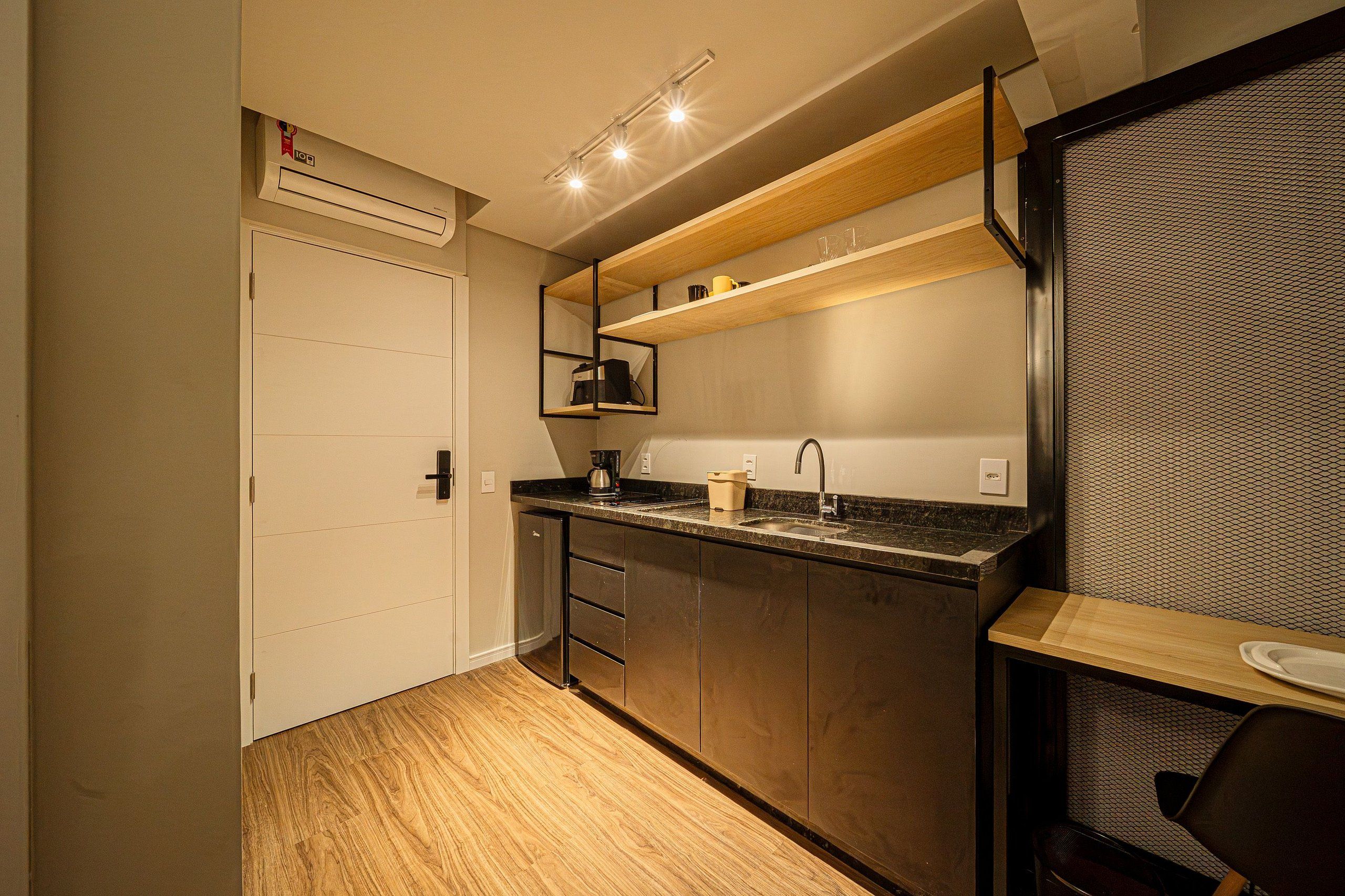 A compact kitchen with a built-in oven, a coffee maker, and a sink.