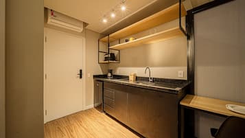 A compact kitchen with a built-in oven, a coffee maker, and a sink.