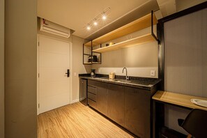 A compact kitchen with a built-in oven, a coffee maker, and a sink. - Apez Smart Studio (Joinville)