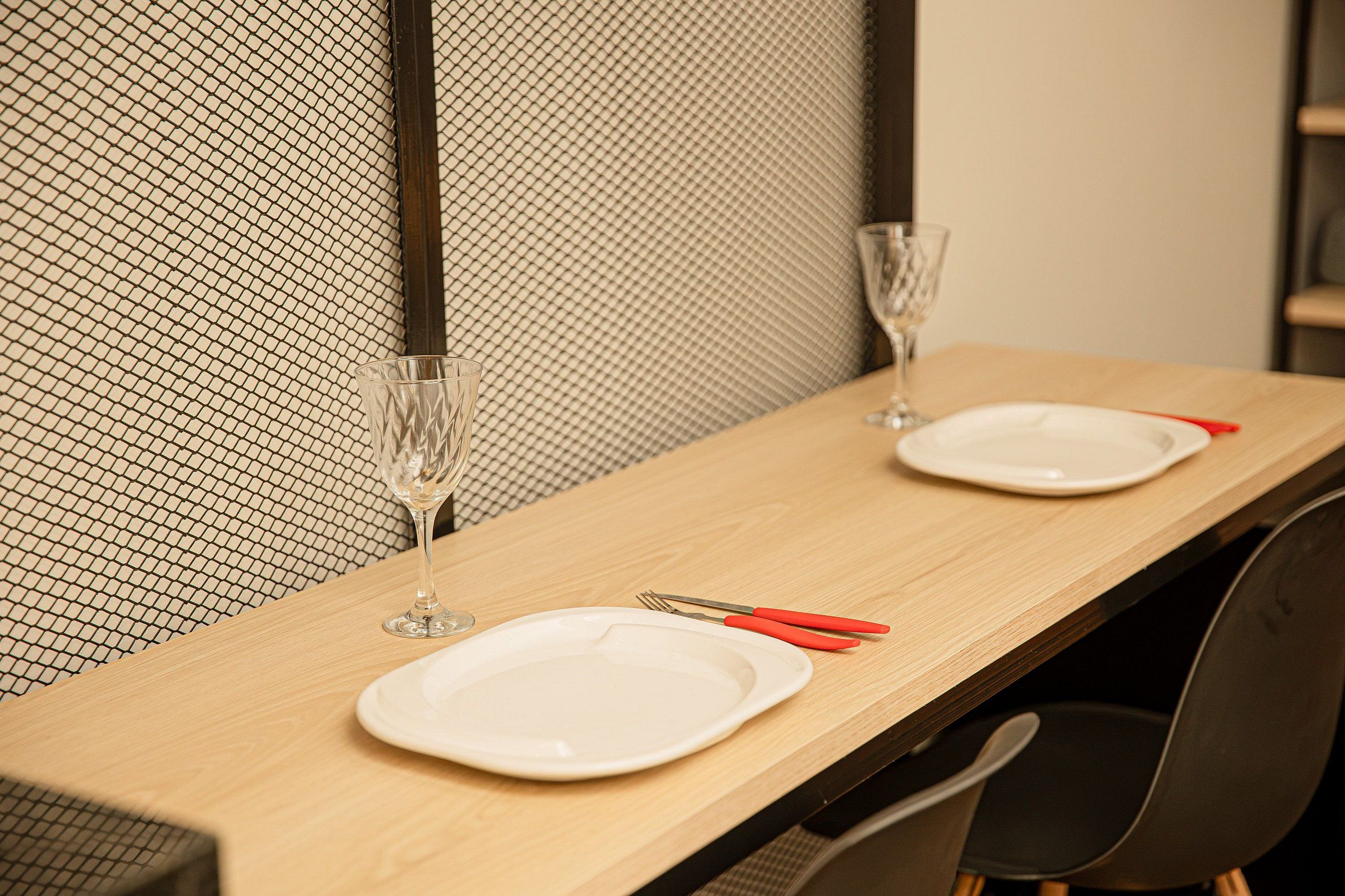 A dining table with two plates, cutlery, and glasses, set against a textured wall.