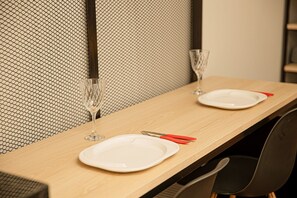 A dining table with two plates, cutlery, and glasses, set against a textured wall.