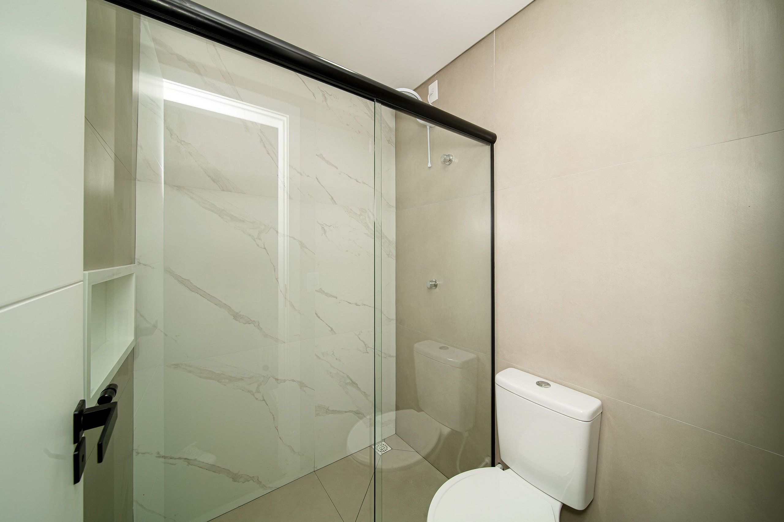Ein Badezimmer mit Duschkabine aus Glas, Toilette und Waschbecken.