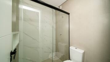 Ein Badezimmer mit Duschkabine aus Glas, Toilette und Waschbecken.