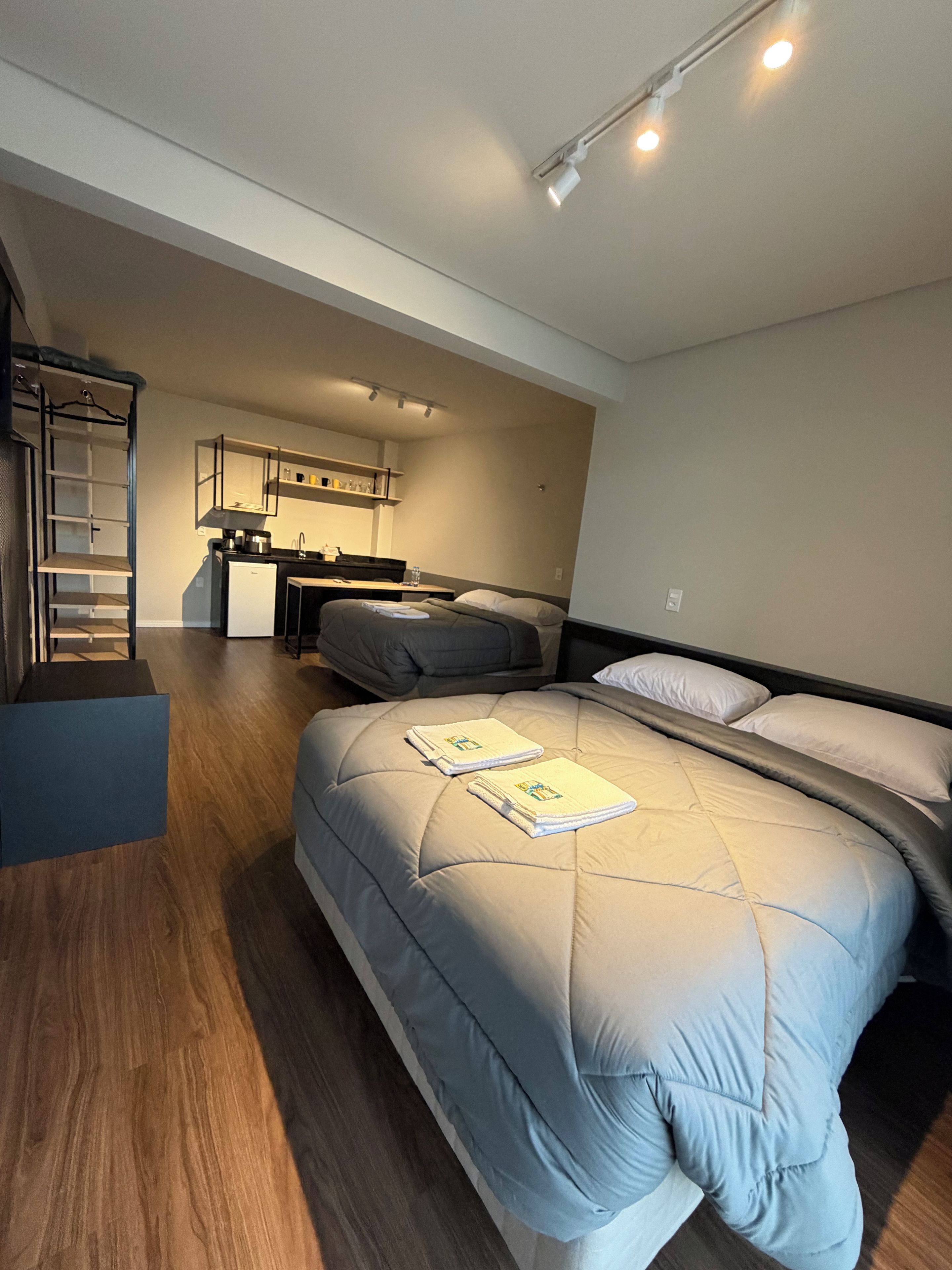 A compact room with a bed, a kitchenette, and a built-in wardrobe.