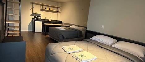 A compact room with a bed, a kitchenette, and a built-in wardrobe.