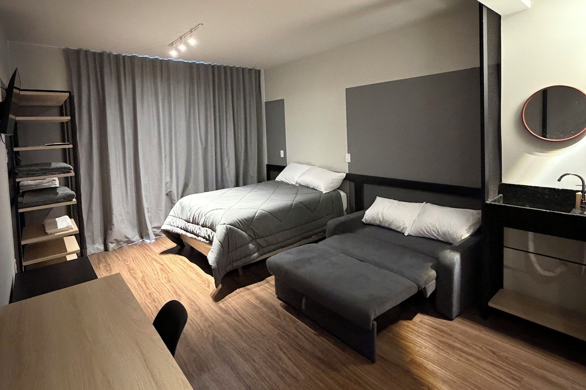 Une chambre d’hôtel moderne équipée de deux lits, d’un bureau, d’une chaise, d’une petite table, d’un miroir et d’une armoire.