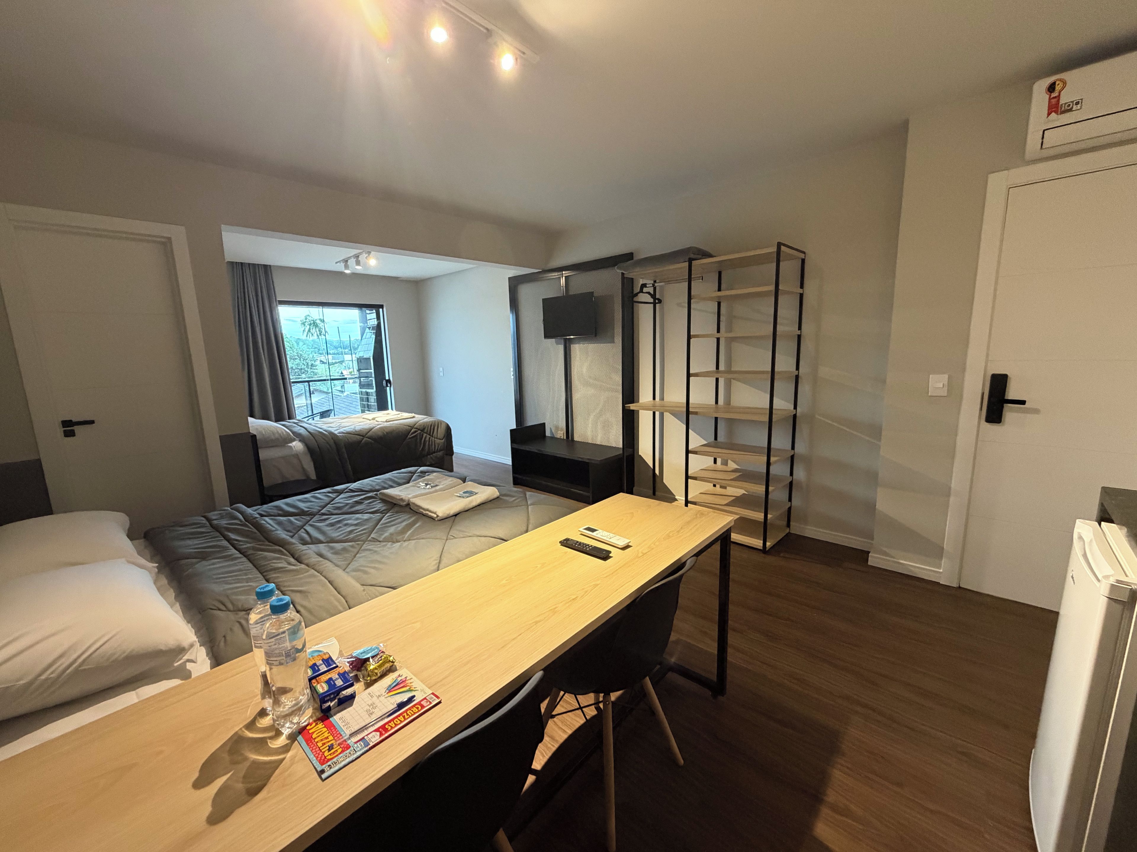 A hotel room with a bed, a desk, a chair, a TV, and a wardrobe.