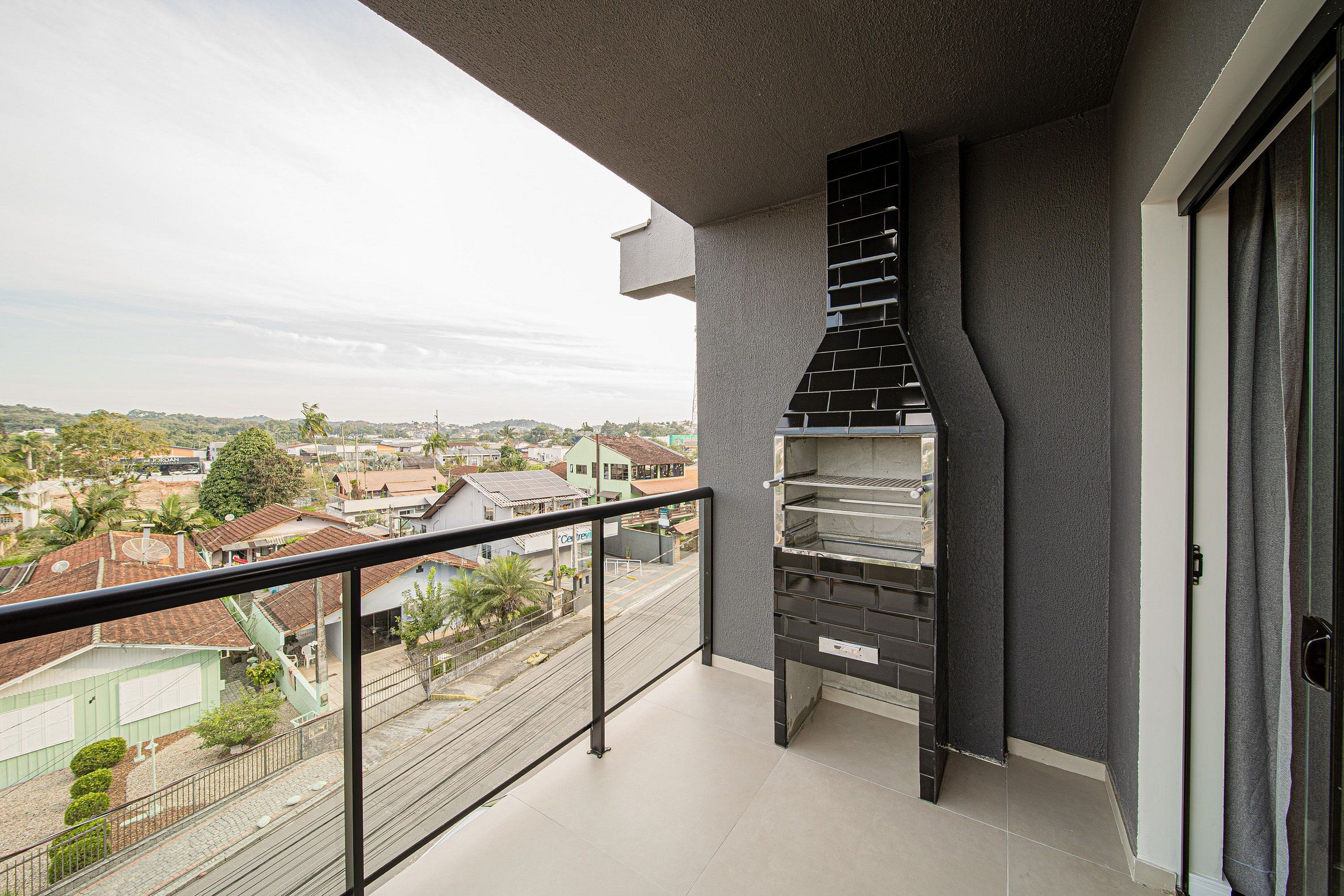 Un balcón con una barandilla negra y vista a una zona residencial.