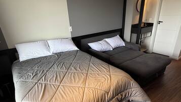 Una cama doble con cubierta acolchada, una mesita de noche y un revistero.