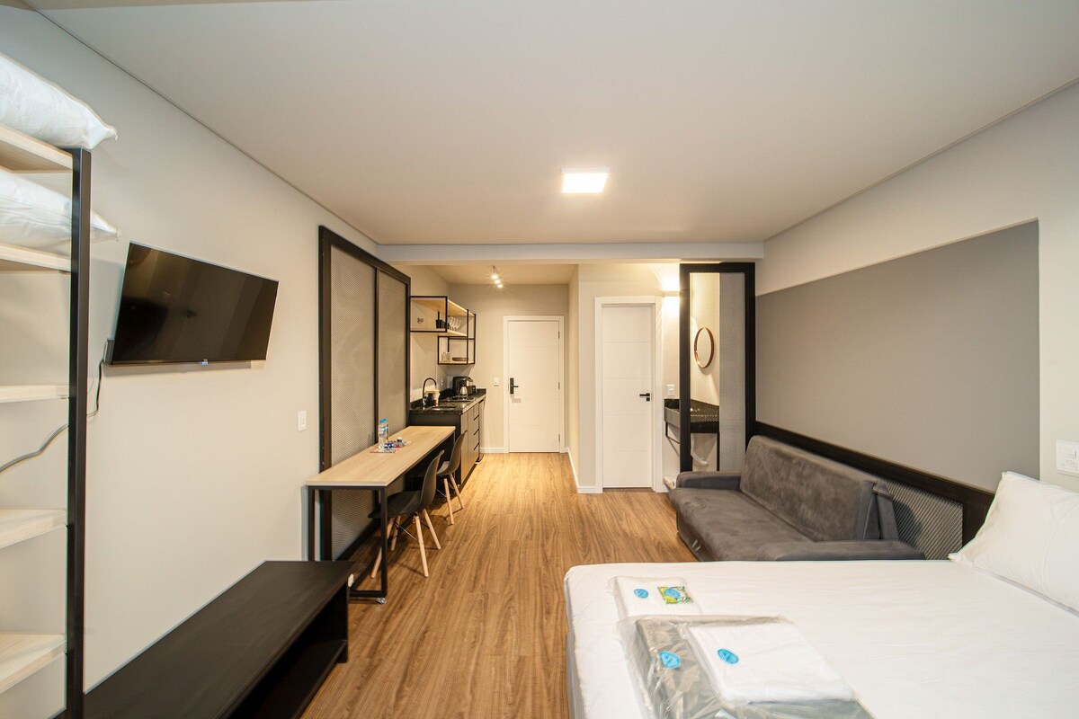 Una habitación de hotel con cama, escritorio, silla, televisión y baño.