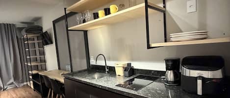 A modern kitchen with a built-in dishwasher, a coffee maker, and a shelf with glasses.