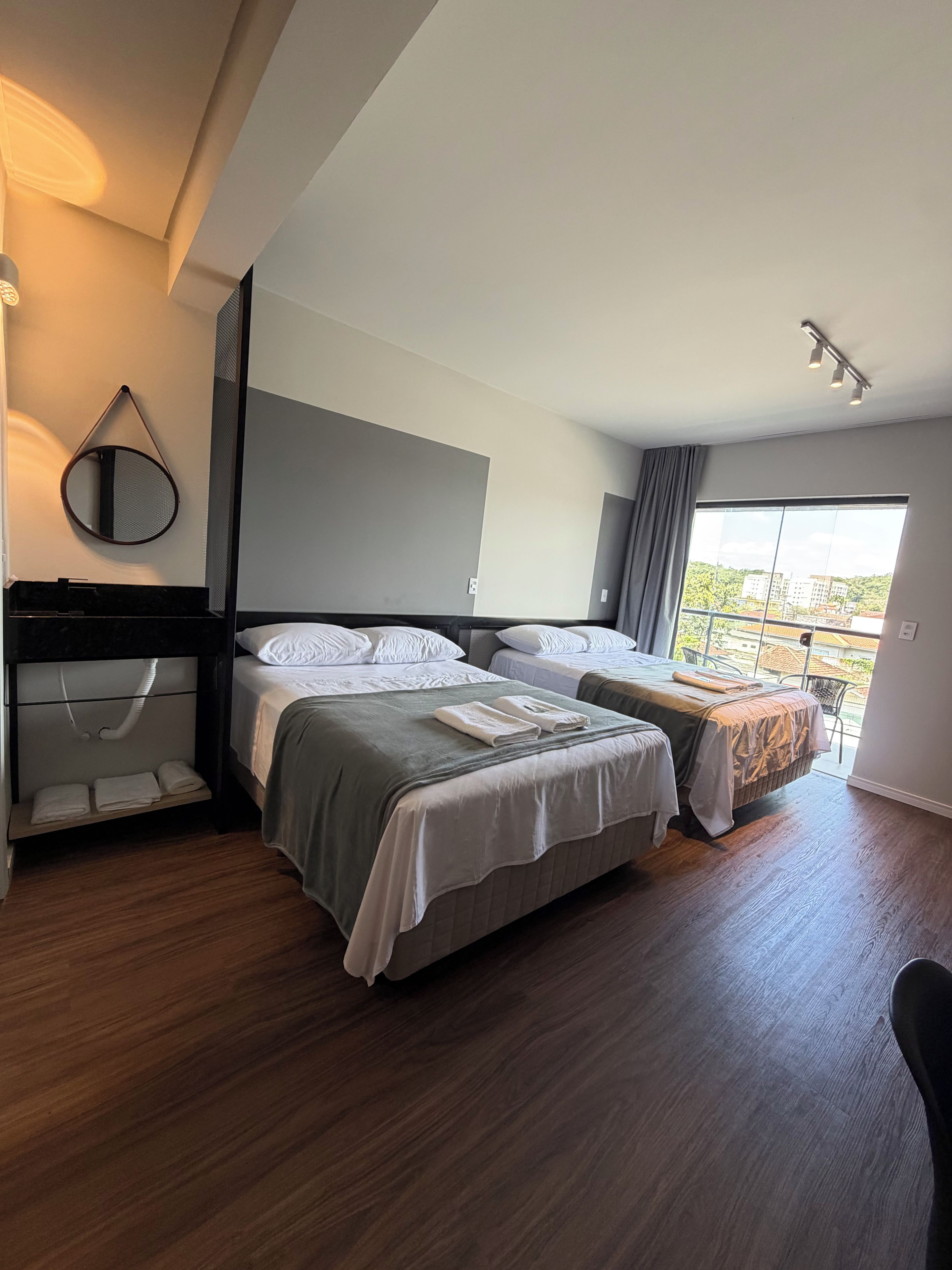 Una camera d'albergo moderna con due letti, un'ampia finestra e un balcone.