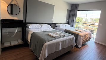 Una camera d'albergo moderna con due letti, un'ampia finestra e un balcone.