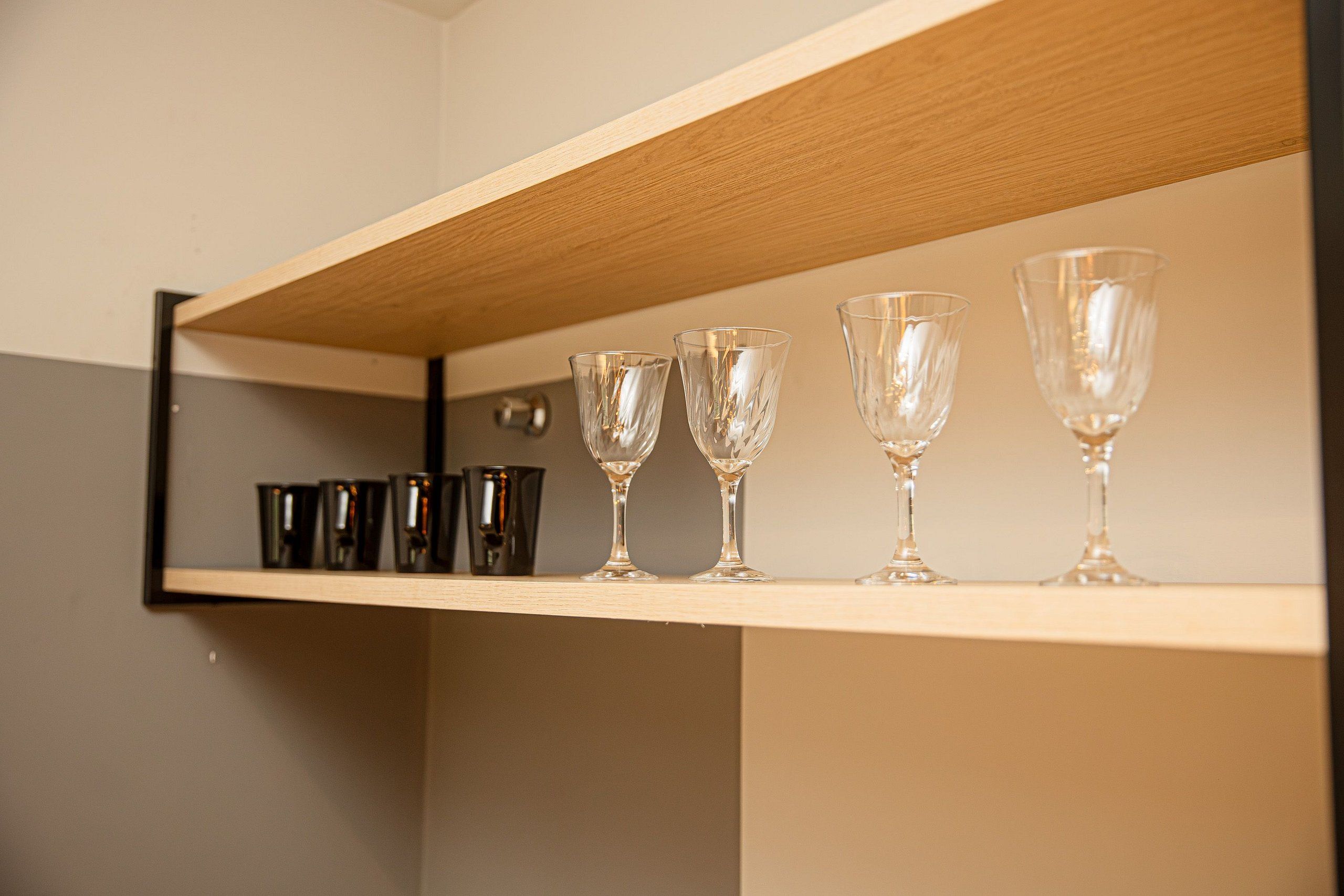 A shelf with various glassware and black cups.