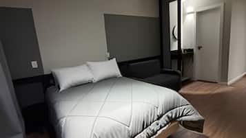 A modern bedroom with a bed, a nightstand, and a door leading to another room.