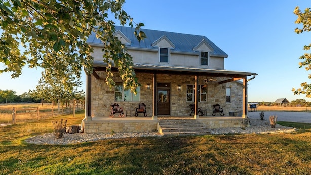 A stone house with a covered porch, two windows, and a door. - TimberRose Ranch | Hot Tub + Hill Country Views (Fredericksburg)