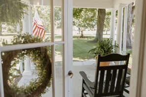 A porch with a bench, a wreath, and an American flag.