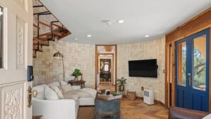 Ein Wohnzimmer mit einer Couch, einem Couchtisch, einem Fernseher und einer Treppe.