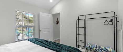 Ein Schlafzimmer mit Bett, Kleiderschrank, Heizkörper und einem Fenster mit Jalousien.