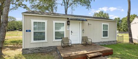 A single-story mobile home with a front porch, two windows, a door, and a number '104' sign.