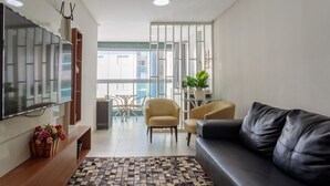 Ein modernes Wohnzimmer mit einer Couch, einem Fernseher und einem gemusterten Teppich.
