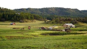 A rural landscape with a barn, a red house, and a tractor in a field.