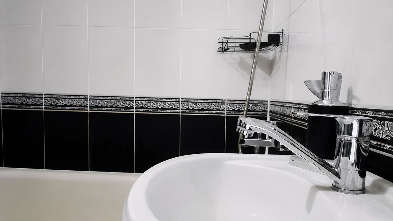 A bathroom with a white sink, chrome faucet, and a showerhead.